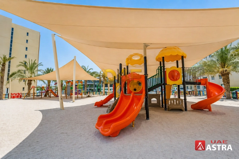 Children’s playground with slides and shaded seating area in residential community.