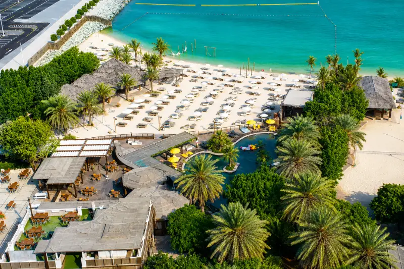 Aerial view of Barasti Beach with pool, palm trees, and Dubai waterfront