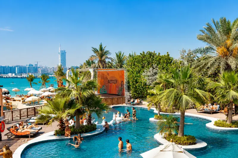 Barasti Beach pool area with palm trees and Dubai waterfront views