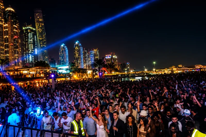 Crowd enjoying nightlife event at Barasti Dubai with Marina skyline views