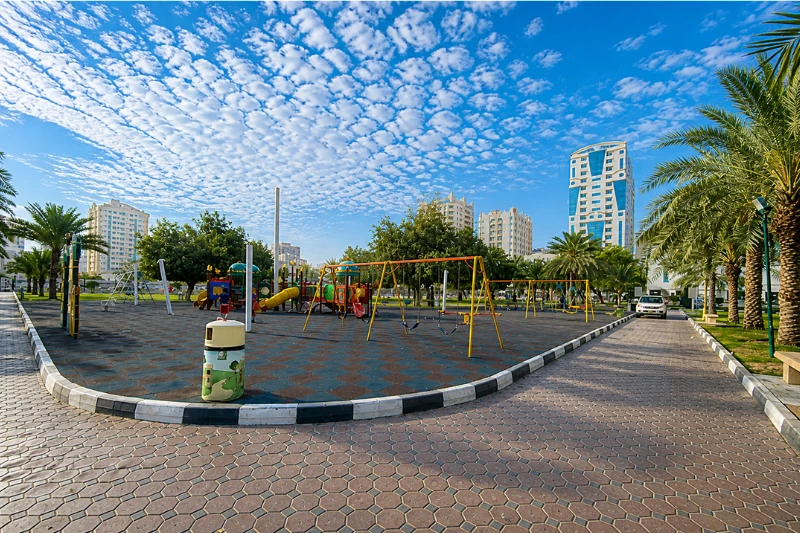 Playground area with swings and walking path in Al Mahatta Park Sharjah