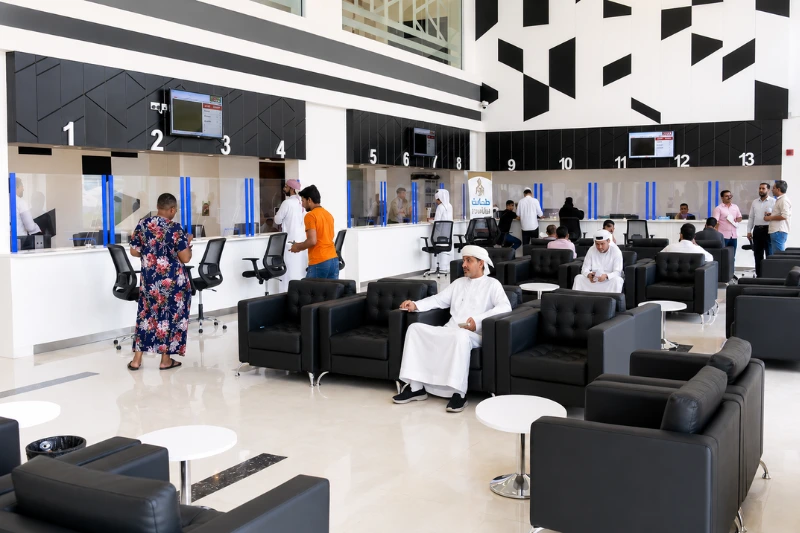 Visitors waiting at customer service counters inside a Dubai immigration service cente