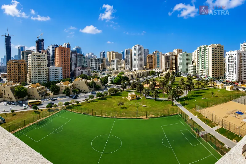Abu Shagara Park with football field, green open spaces, and surrounding residential buildings in Sharjah