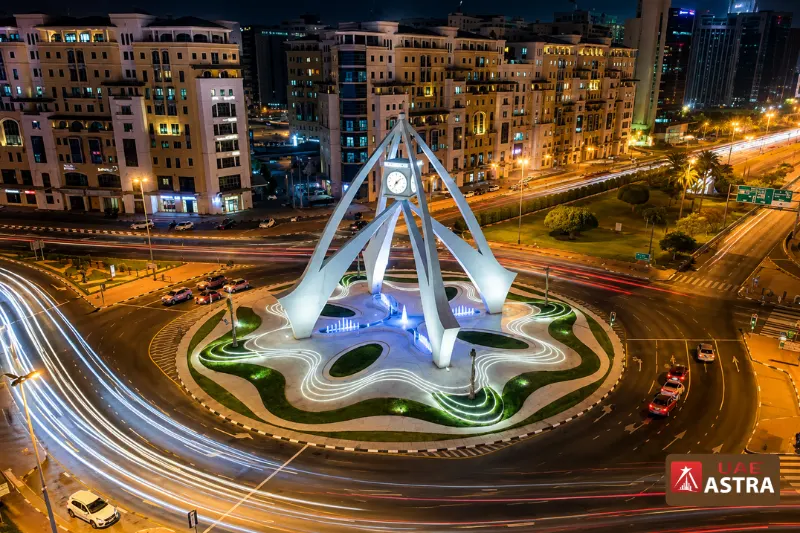 Aerial night view of Clock Tower Roundabout with illuminated fountain and traffic trails in Deira Dubai
