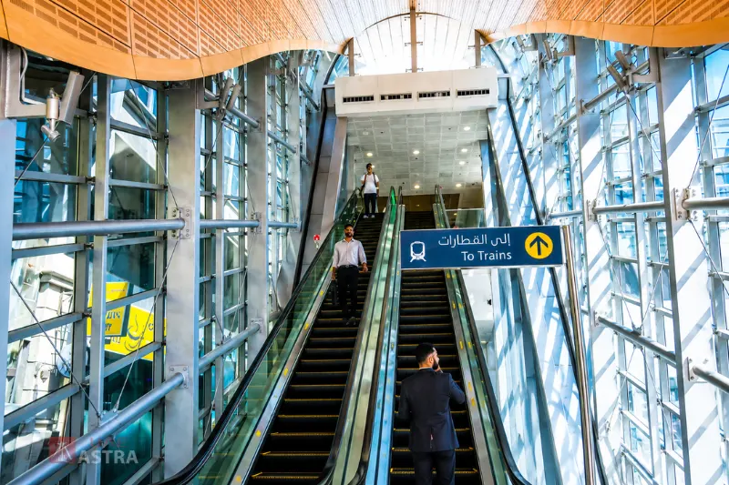 Escalators inside Al Qiyadah Metro Station leading to train platforms with clear passenger direction signage