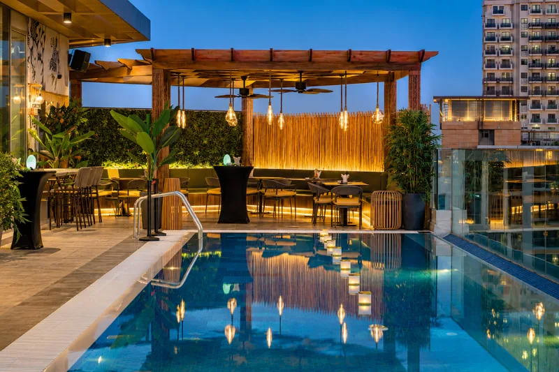 Luxury rooftop pool and outdoor dining area at a Jaddaf Waterfront hotel with a modern city backdrop