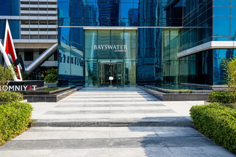 Main entrance of Bayswater Tower Business Bay featuring the modern glass façade and OMNIYAT branding