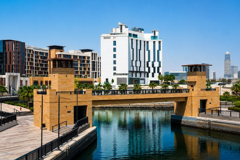 Modern pedestrian bridge and waterfront canal at Jaddaf Waterfront surrounded by contemporary Hotel buildings and Dubai Creek views