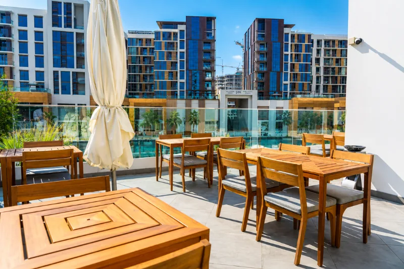 Outdoor dining terrace at a Jaddaf Waterfront hotel overlooking modern residential buildings and landscaped surroundings