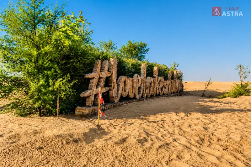 Al Qudra Lake desert landscape with a wooden sign and greenery