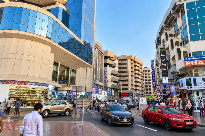 Busy commercial street in Al Sabkha, Deira, with shops, pedestrians, traffic and mixed-use buildings