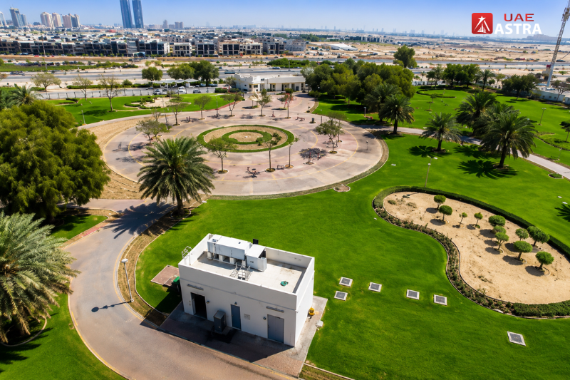 Aerial view of Al Quoz Pond Park with green lawns and circular walking paths in Dubai