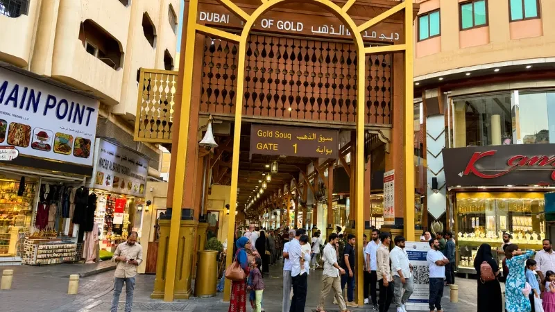 Dubai Gold Souk Gate 1 entrance in Deira with shoppers and jewellery stores lined along the historic market