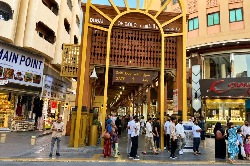 Dubai Gold Souk Gate 1 entrance in Deira with shoppers and jewellery stores lined along the historic market
