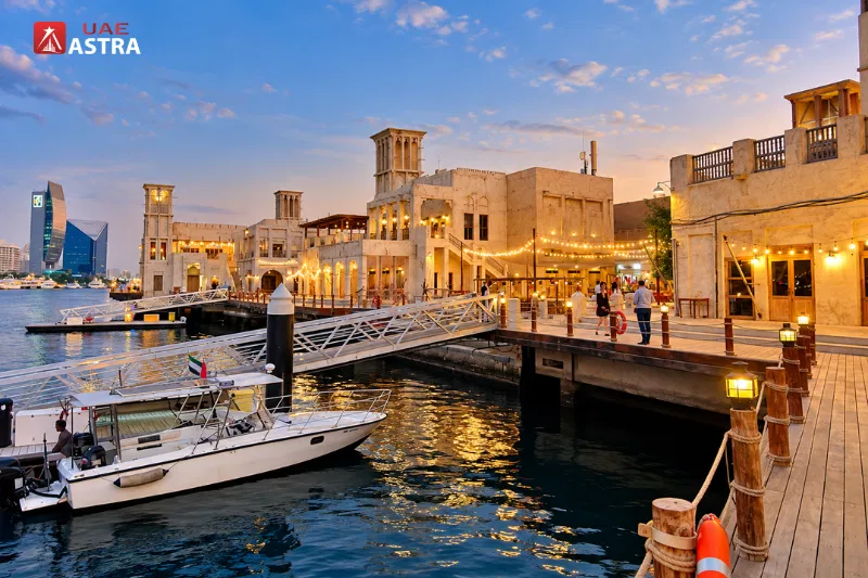 Al Seef waterfront marina and heritage buildings along Dubai Creek at sunset
