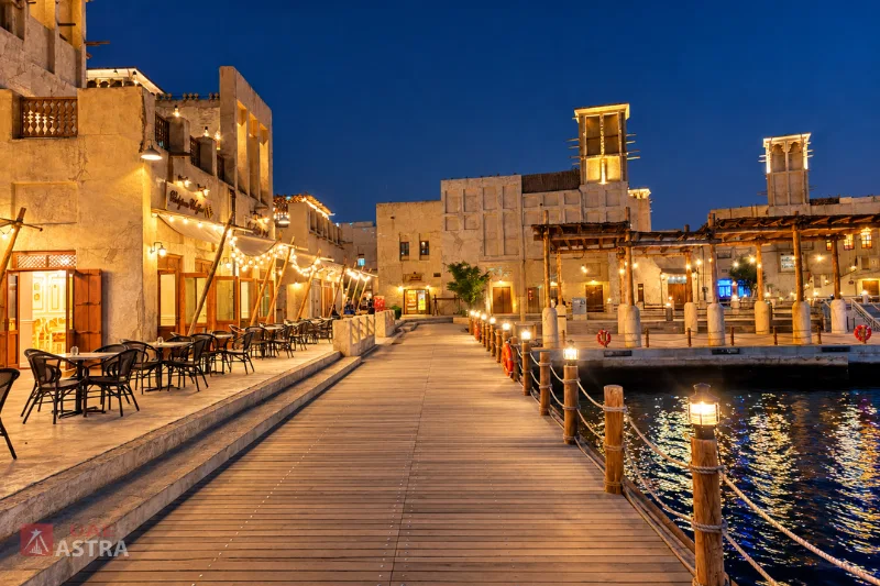 Al Seef waterfront promenade at night with illuminated heritage buildings and creekside dining