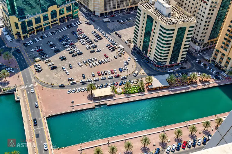 Aerial view of Ameer Bu Khamseen Tower, parking area and waterfront in Sharjah