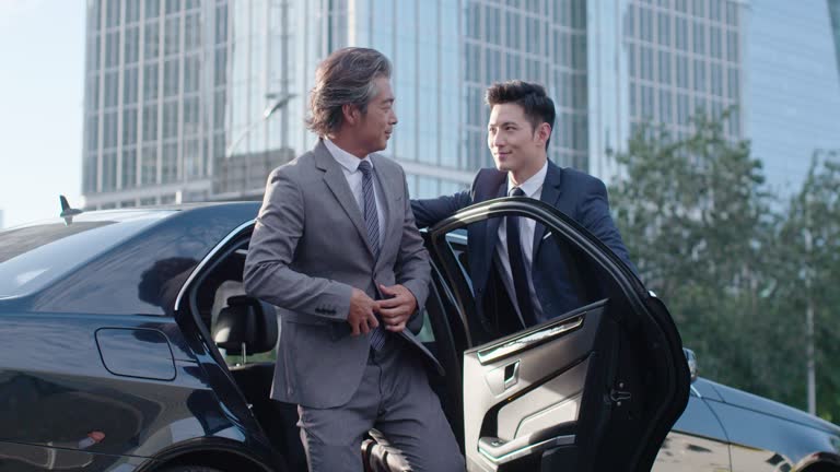 Chauffeur assisting a passenger into a luxury car