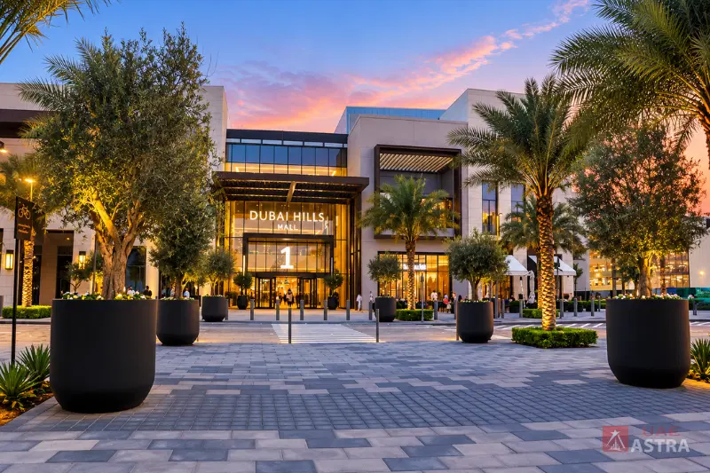 Dubai Hills Mall main entrance with landscaped walkways and palm trees at sunset