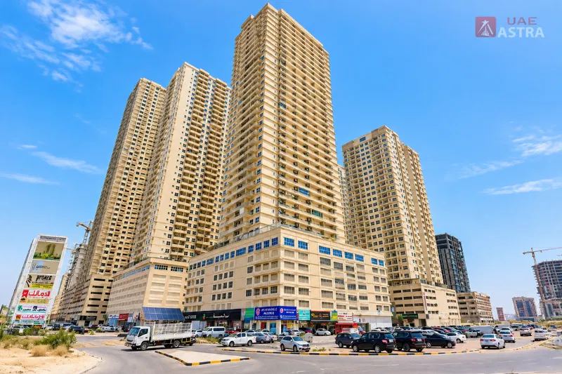 Emirates City Ajman residential towers with ground-floor shops and parking areas